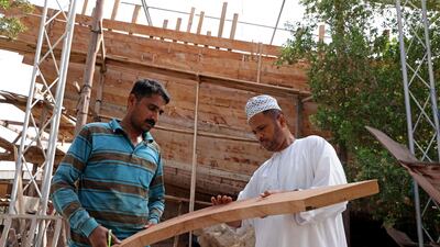 Ali al-Araimi (R) inspects a piece of wood at a shipyard in the Omani port city of Sur, south of the capital Muscat, on June 19, 2022. (Photo by MOHAMMED MAHJOUB / AFP)