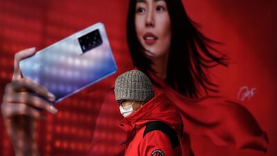A man wearing a face mask walks by a smartphone advertisement at a subway station in Beijing. AP Photo