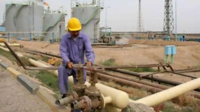 A refinery worker controls a valve on an oil pipeline.
