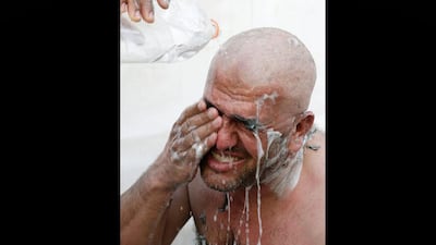 A man who has his head ritually shaved rinses, after casting stones at a pillar during Jamarat