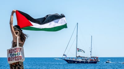 A woman on the quay of San Giovanni Li Cuti raises the Palestinian flag before the Freedom flotilla boat Madleen set sail for Gaza on June 1. Getty Images