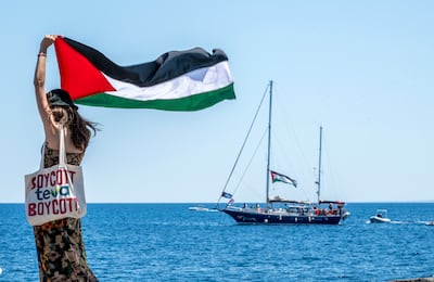 A woman raises the Palestinian flag as the Madleen sets sail from Catania, Italy. Getty Images