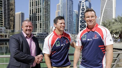 Henry Paul, centre, poses with Dragons chairman Mike Lewis, left, and Paul Hart. Jeffrey E Biteng / The National