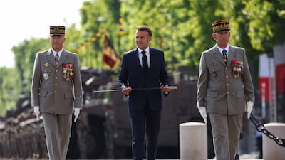 France's President Emmanuel Macron (C) presents a new sword to the Flame of the Unknown Soldier Committee flanked by France's Chief of the Defence Staff General Thierry Bukhard (L) and French Military Governor of Paris (GMP) Loic Mizon before the Tomb of the Unknown Soldier at the Arc de Triomphe as part of the 100th anniversary of the Organisation du Bleuet de France (ONACVG) during the annual traditionnal Bastille Day parade on the Champs-Elysees Avenue in Paris on July 14, 2025. (Photo by Abdul Saboor / POOL / AFP)