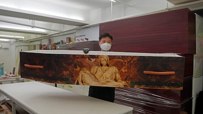A worker lifts up a paper coffin at LifeArt's factory in Hong Kong. LifeArt says its alternative, cardboard coffins are environmentally friendly.