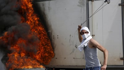 A Palestinian protester uses a sling to hurl stones towards Israeli troops during clashes in the West Bank city of Hebron on October 18, 2015. Mussa Qawasma/Reuters