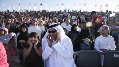 Khamis Al Kaabi and his niece Mariam Al Kaabi, top, protect themselves as Al Fursan jets roar by the grandstand at the 10th Annual Al Ain Aerobatics Show. Silvia Razgova / The National