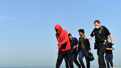 Migrants are escorted to be processed after being picked up in Dungeness. The previous record was 828 migrants on August 21. AFP