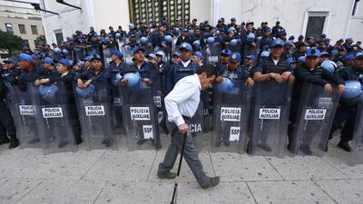 A man walks in front of police officers during a demonstration by members of the teachers' union CNTE at Reforma avenue in Mexico City on February 11, 2015. Tensions were high in Mexico City on Wednesday as riot police turned out en masse to stop teachers from marching on the capital's Reforma boulevard on the third day of protests against unpaid wages and threats to workers rights in Mexico's creaking education system. Edgard Garrido / Reuters