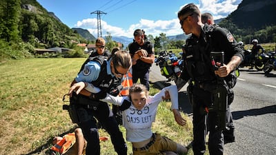 French gendarmes remove environmental protestors from the race route. AFP