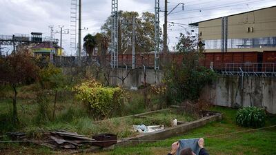 A man is hanging out a piece of cloth to dry in the yard of the 5a Akatsiy house as a freight train drives past. Alexander Zemlianichenko / AP Photooto