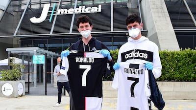 Juventus fans wearing protective face masks and gloves display shirts with Cristiano Ronaldo's name as players and staff arrive for training at Juventus Training Center. Reuters