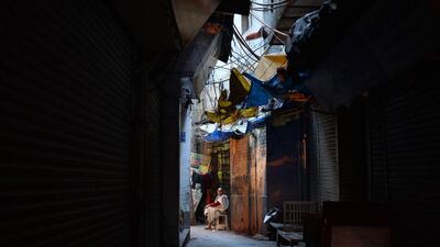 A woman sits inside a closed market lane in the old quarters of New Delhi. Chandan Khanna / AFP