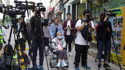 A woman is wheeled past journalists outside a polling centre in Hong Kong. AP Photo