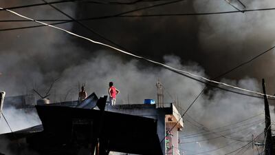 epa05040792 Filipinos engulfed in smoke stand on top of a house during a fire in Mandaluyong City, east of Manila. Mark R Cristino / EPA