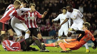 Sunderland goalkeeper Simon Mignolet slides to block Danny Graham's attempt on goal.