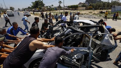 Palestinians move the remains of a vehicle destroyed in an Israeli strike in Deir Al Balah, in the central Gaza Strip, on Tuesday. Reuters