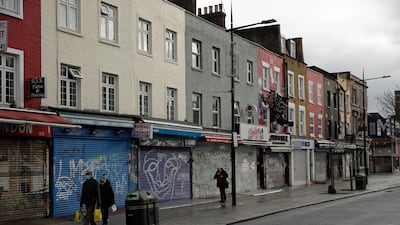 People walk past temporarily closed shops in Camden Town, an area of London usually bustling with tourists and visitors to its market. AP Photo