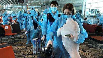 A Vietnamese woman carries a stuffed animal while boarding a repatriation flight from Singapore to Vietnam, at Changi airport, Singapore. Reuters