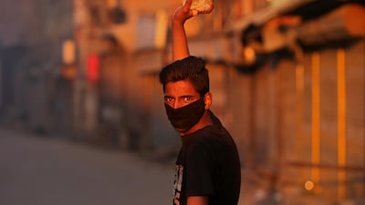 A masked Kashmiri demonstrator throws a stone at Indian police during a protest after the end of the second phase of general election in Srinagar April 18, 2019. Reuters