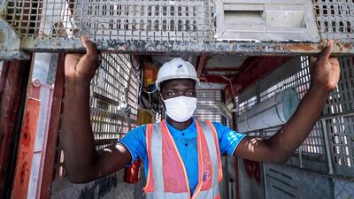 An elevator technician rolls down the metal safety doors of the lift at the construction site. Victor Besa / The National