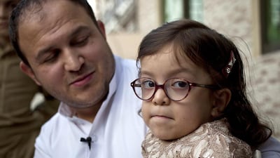 Maria Ullah, 6, who is suffering from Morquio syndrome, or MPS, a rare genetics disorder, sits on her father Shahid's lap in Rawalpindi, Pakistan, on Thursday, October. 20, 2016. The US embassy in Islamabad have twice refused her a visa to travel to the US where she has been offered life-changing surgery for free. B.K Bangash / AP