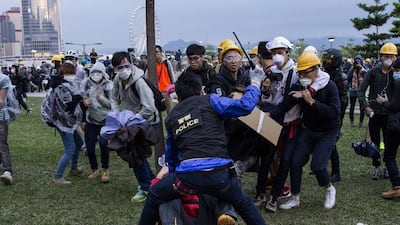 A police officer, centre, raising his baton at a group of pro-democracy protesters as he restrains a protester on the ground at Tamar, near the government headquarters in the Admiralty district of Hong Kong on December 1, 2014. Dale de la Rey/AFP Photo