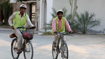 Two cyclists wear protective headgear and a high-visibility vest - as is mandatory under a law issued eight years ago. Pawan Singh / The National