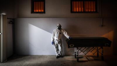 epa08976018 A funerary worker wearing a protective suit stands next to a coffin with a body of a man, who died of covid-19 in Amadora, outskirts of Lisbon, Portugal, 29 January 2021 (issued on 30 January 2021). This week Portugal surpassed 300 covid-19 deaths in a single day, a new maximum of deaths since the beginning of the pandemic. Portuguese government imposed a 14-day national lockdown including foreign travel restrictions, as the country is fighting the surge of new variant of coronavirus Covid-19 that puts the health care system under severe pressure. EPA/MARIO CRUZ ATTENTION: This Image is part of a PHOTO SET