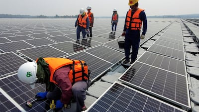 A worker kneels by a solar cell panel over the water surface of Sirindhorn Dam in Ubon Ratchathani, Thailand. Reuters