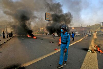 A mask-clad policeman walks near tires set aflame by Sudanese protesters marking the first anniversary of a raid on an anti-government sit-in. AFP