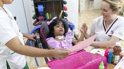 Meznah Basaloum painting a flower with Patricia Smith, a physiotherapist at Amana Healthcare. Reem Mohammed / The National