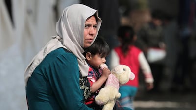 An internally displaced child carries a stuffed animal as he sits on a woman's lap at a makeshift camp in Afrin, Syria. REUTERS