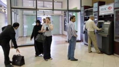 Customers queue at an HSBC ATM machine at Marina Mall.