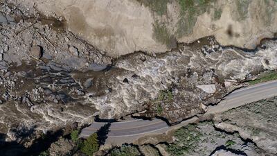 Receding floodwaters flow past sections of a road washed away at Yellowstone National Park, US. Officials are hopeful that next week they can reopen the southern half of the park, which includes Old Faithful geyser. AP