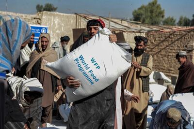Afghans carry sacks of grains distributed as aid by the World Food Programme in Kandahar. AFP