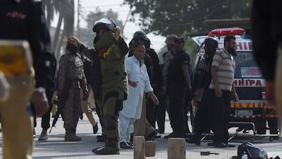A bomb disposal squad member warns onlookers before checking a bag belonging to an attacker outside the Chinese consulate in Karachi. AFP