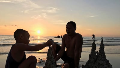 A father and son build sandcastles. AP Photo