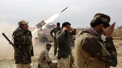 Shi'ite fighters cover their ears as a rocket is launched during a clash with Islamic State militants in the town of al-Alam, Iraq. Thaier Al Sudani / Reuters