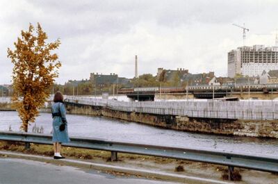 A woman looks at the Berlin Wall along the Spree river in central Berlin in 1980. In the background the Charite Hospital is under construction. AP Photo