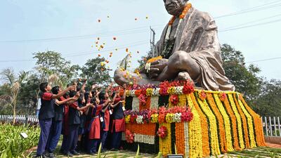 School students scatter flowers on the statue of Mahatma Gandhi on his death anniversary in Hyderabad on January 30, 2023. - The death anniversary of Gandhi, who is widely known in India as Bapu (father), is also observed as Martyr's Day in the country. (Photo by NOAH SEELAM / AFP)