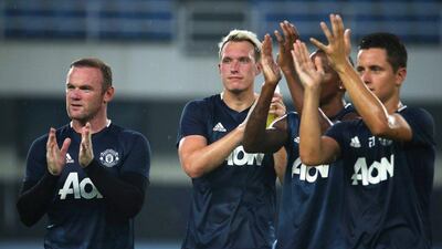 Manchester United players Wayne Rooney (L), Phil Jones (C) and Ander Herrera (R) applaud fans after their training session at the Olympic Sports Center in Beijing, China, 24 July 2016. How Hwee Young / EPA