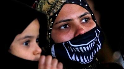 A resident of the Tahya Misr housing project in Al Asmarat district wears a face mask and carries her son in Al Mokattam, east of Cairo. Reuters