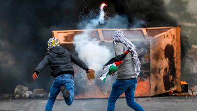 A Palestinian man throws back a tear gas canister during clashes with Israeli forces at a Land Day protest. AFP