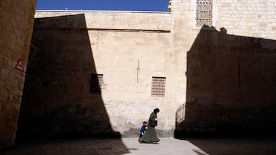A Palestinian woman walks with a child past a shadow of a cross cast by the Church of the Nativity, in the West Bank town of Bethlehem, before Christmas in this December 16, 2010 file photo. UNESCO granted endangered World Heritage status and funding for repairs to the site seen by Christians as Jesus's birthplace in the West Bank city of Bethlehem despite objections from the United States and Israel. Thirteen members of the World Heritage Committee out of twenty one voted in favour of the move at a meeting in St.Petersburg. The decision was met by a standing ovation. Six members voted against and two abstained. REUTERS/Ammar Awad/Files (WEST BANK)