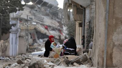 Women and children sit wrapped in blankets outside a collapsed building in Syria, where February's earthquake added to the humanitarian toll of war. AFP