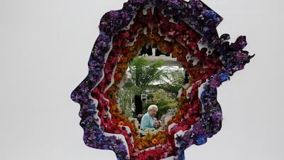 Britain’s Queen Elizabeth II is seen through a gap of a floral exhibit by the New Covent Garden Flower Market at the Chelsea Flower Show. Adrian Dennis / AFP Photo