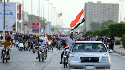 A man waves an Iraqi national flag as he rides from out the window of a car driving ahead of motorcycles and other protesters in Najaf. AFP