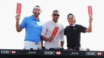 From left, Dustin Johnson, Reggie Yates and Rickie Fowler hold up “Noise please” placards. The players competing at the Abu Dhabi HSBC Championship will approach the first tee at the National Course accompanied by music. Courtesy Four Communications