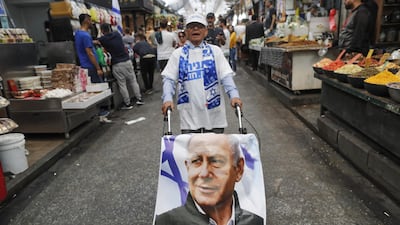 A supporter of the Likud party pushes a trolley covered with a poster bearing a portrait of Israeli Prime Minister Benjamin Netanyahu in Jerusalem. AFP